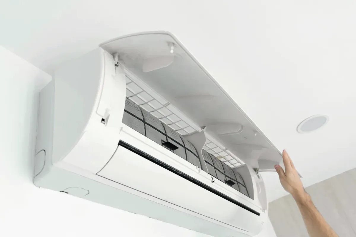 Hand opening the cover of a wall-mounted ductless air conditioner