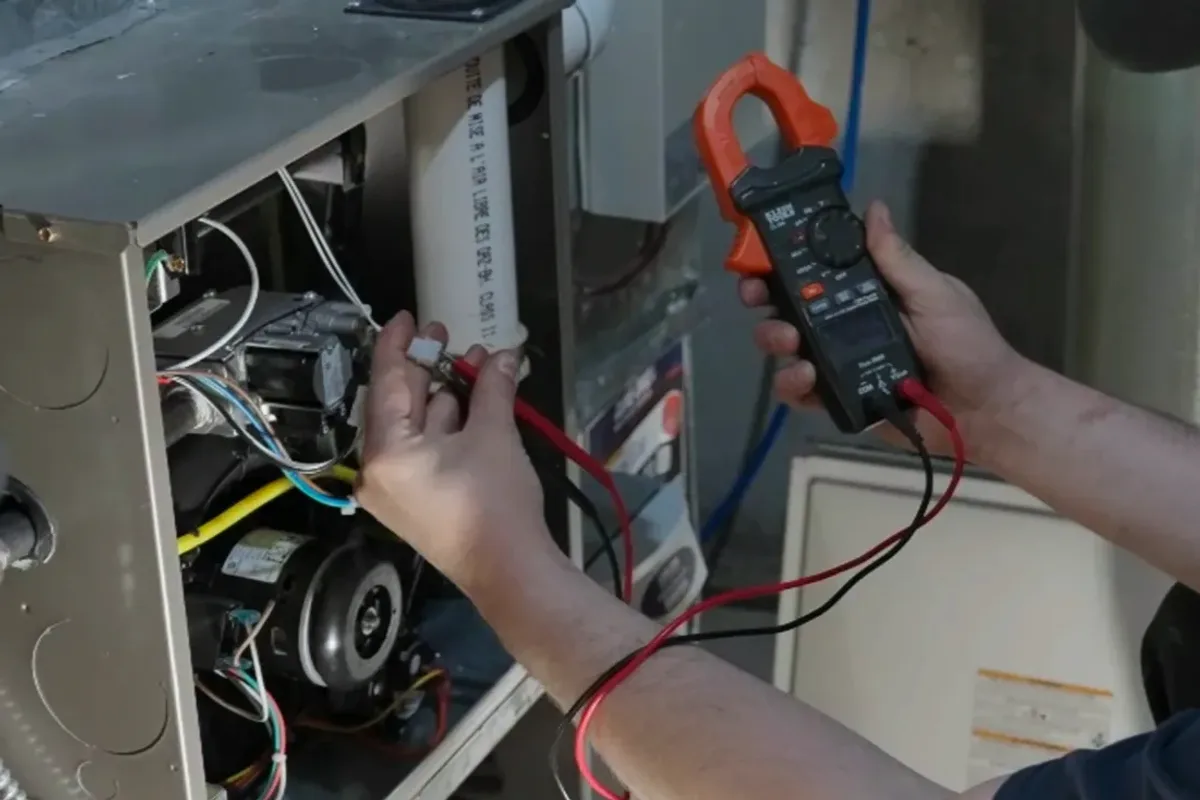Technician testing a furnace's wiring with a clamp meter